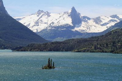 Scenic view of lake by snowcapped mountains against sky