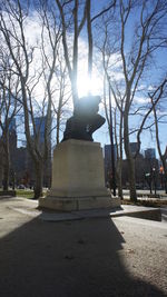 Statue amidst bare trees against sky