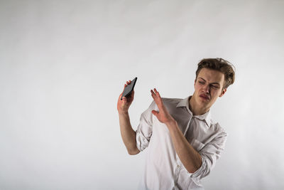 Portrait of young man standing against white background