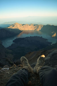 Low section of person relaxing on mountain against sky