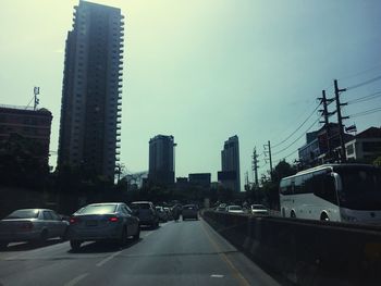 Cars on street in city against sky