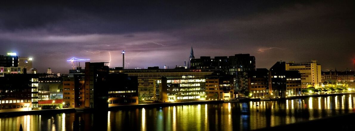 architecture, illuminated, building exterior, built structure, city, night, sky, cityscape, skyscraper, water, river, urban skyline, modern, cloud - sky, waterfront, tower, office building, reflection, tall - high, dusk