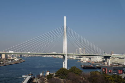 Suspension bridge over river against clear blue sky
