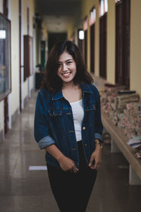 Portrait of smiling young woman standing in corridor