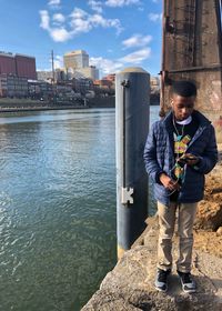 Boy standing on retaining wall by river