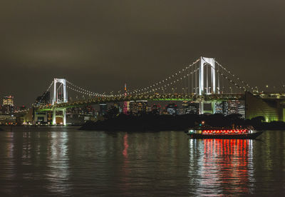 Illuminated bridge over river against sky at night