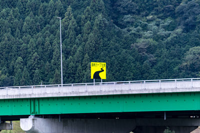Yellow bridge over mountain against trees