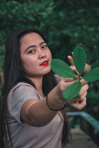 Portrait of young woman holding plant