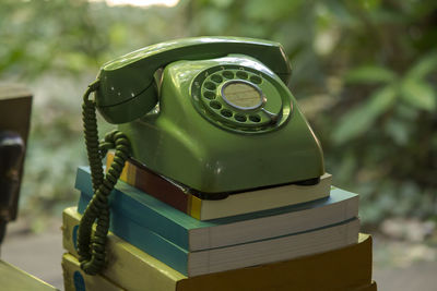 Close-up of rotary phone on stacked books outdoors