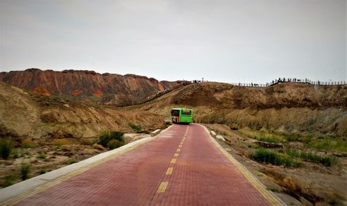 Road leading towards mountain against clear sky