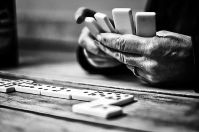 Cropped hands on man playing dominoes on table