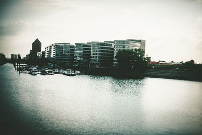 Buildings by river against sky in city