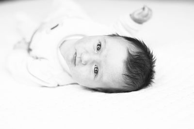 Portrait of cute baby lying on bed at home