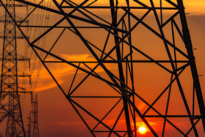 Low angle view of silhouette electricity pylon against sky during sunset