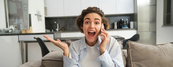 Young woman using phone while sitting on sofa at home