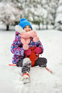 Full length of child sitting in snow outdoors