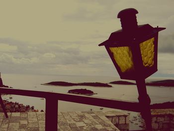 Lighthouse on beach against cloudy sky