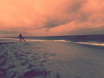 Silhouette people on beach against sky during sunset