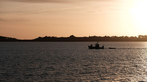 Silhouette boats sailing in sea against sky during sunset