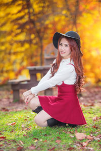 Portrait of woman crouching at park during autumn