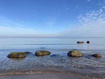 Rocks in sea against blue sky