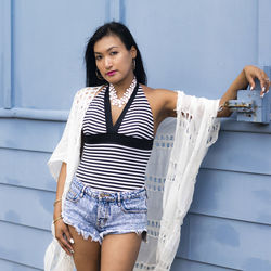 Portrait of smiling young woman standing against wall