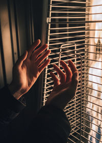 Close-up of hand holding metal against window