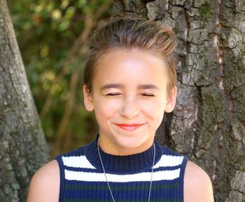 Portrait of smiling young woman against trees