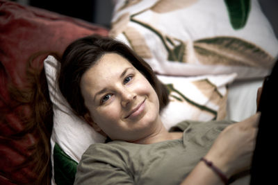 Portrait of woman lying on bed at home