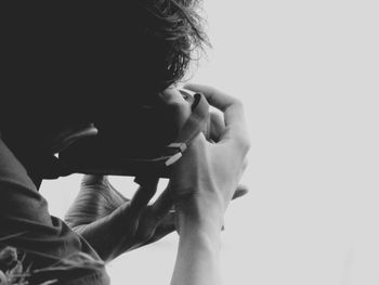 Cropped image of man photographing with camera against white background