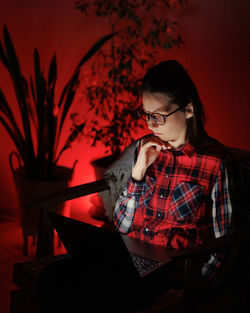 Young woman using mobile phone while sitting on table