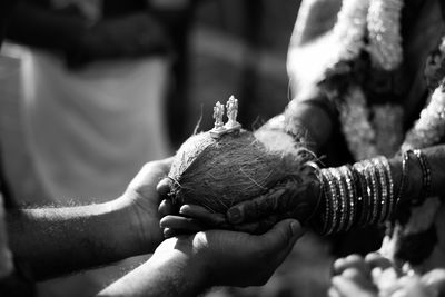 Cropped hands of couple holding coconut during wedding ceremony