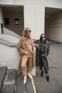 Two girlfriends in matching spring autumn  clothes standing and taking outside in urban background