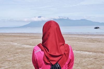 Rear view of woman on beach against sky