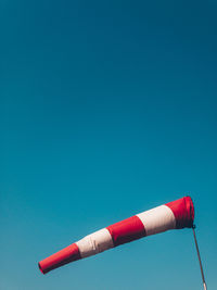 Low angle view of red lighthouse against clear blue sky