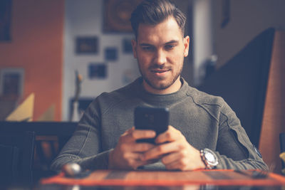 Smiling man using phone in restaurant