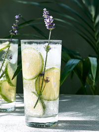 Cool lavender lemonade with lime slices and lavender flower on the table near dark green wall