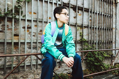 Contemplative boy looking away while sitting on railing