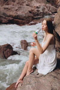 Young woman drinking water from rocks