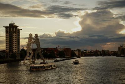 City at waterfront against cloudy sky