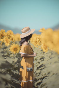 Midsection of woman with yellow flowers against sky