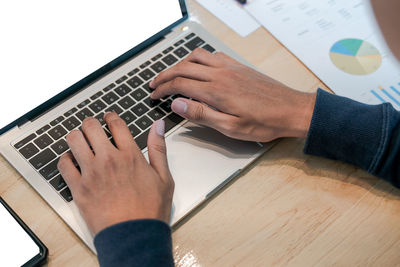 Cropped hands of businessman using laptop at desk in office