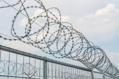 Low angle view of barbed wire against sky