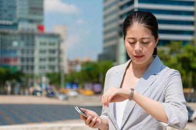 Businesswoman checking time on street in city