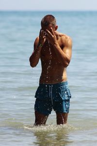 Shirtless man swimming in lake