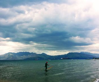 Man standing in sea against sky