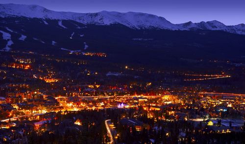 Illuminated townscape against snowcapped mountains