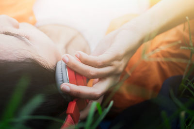 Close-up of woman listening music on headphones while lying on grassy field