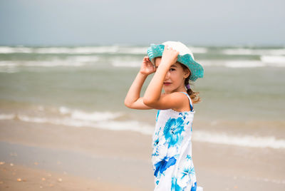 Portrait of young woman standing at beach