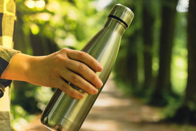 Close-up of unrecognizable female hand holding water bottle. reusable steel thermo water bottle in